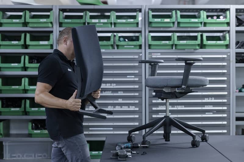 Die R&uuml;ckenlehne eines gebrauchten, hochwertigen B&uuml;rostuhls wird abgenommen